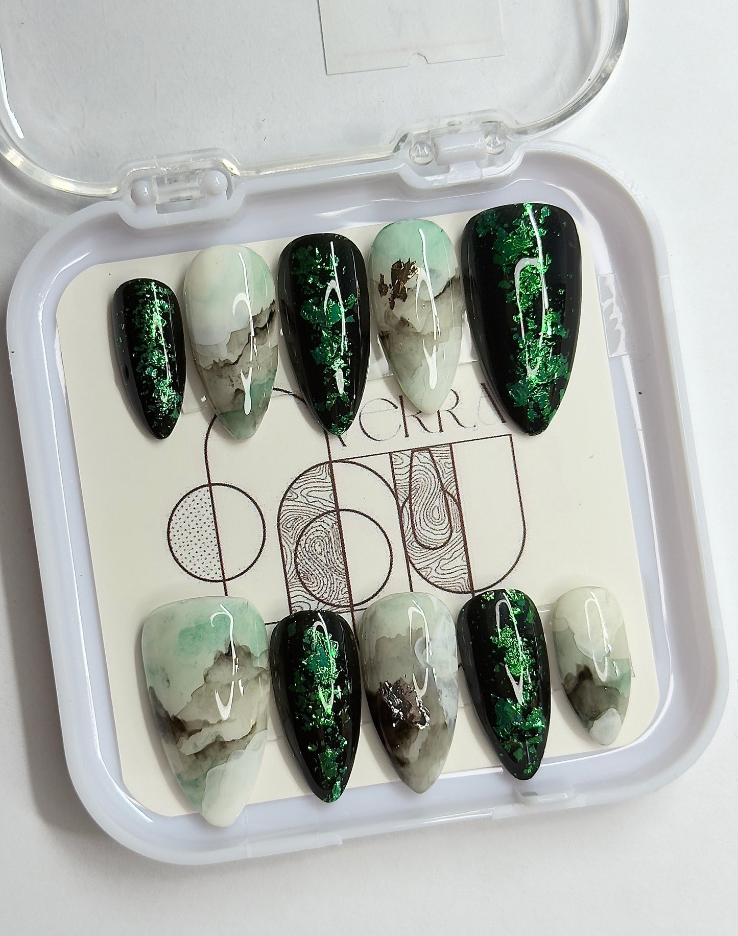 Set of green and white marbled nail art designs in a clear case.