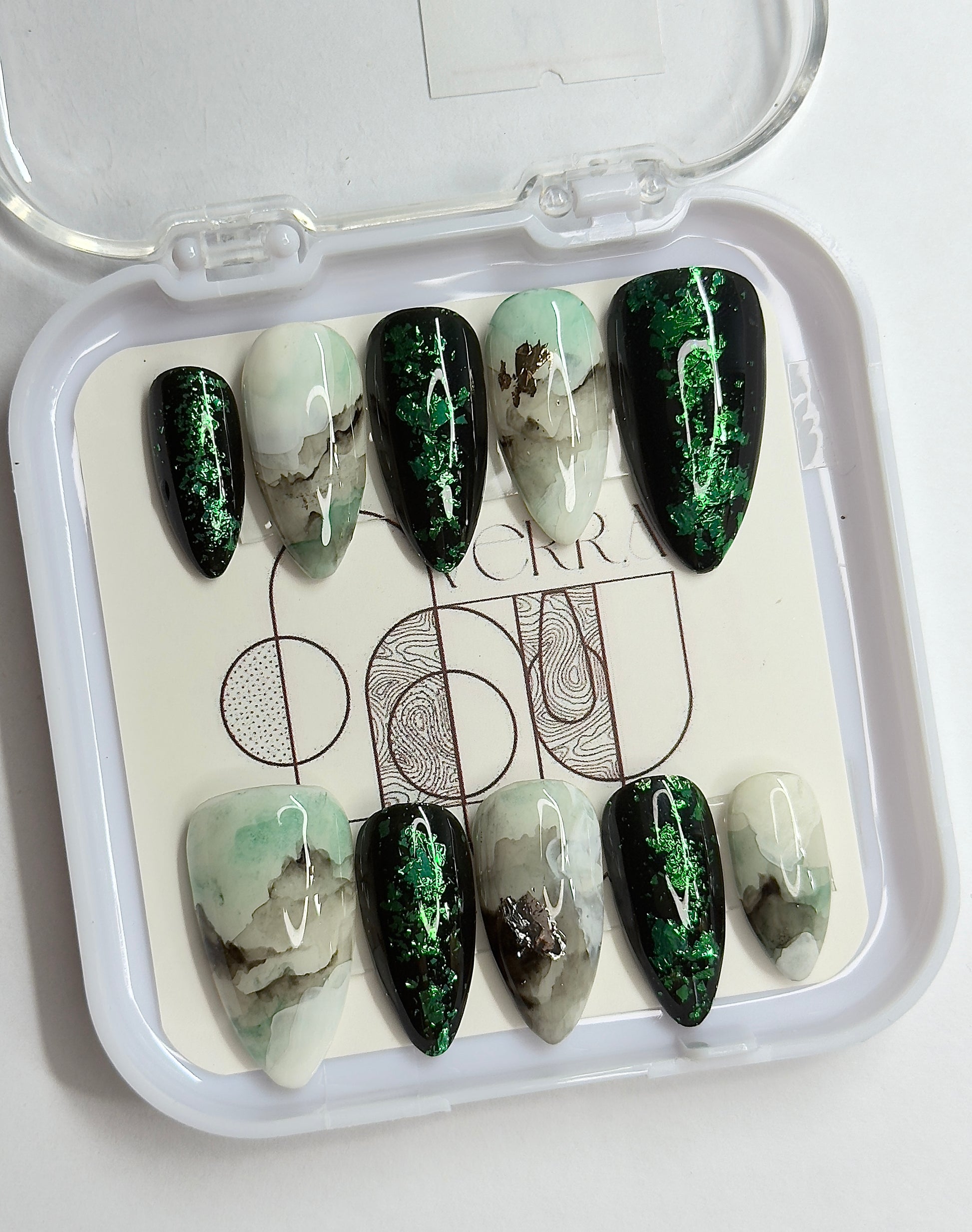 Set of green and white marbled nail art designs in a clear case.